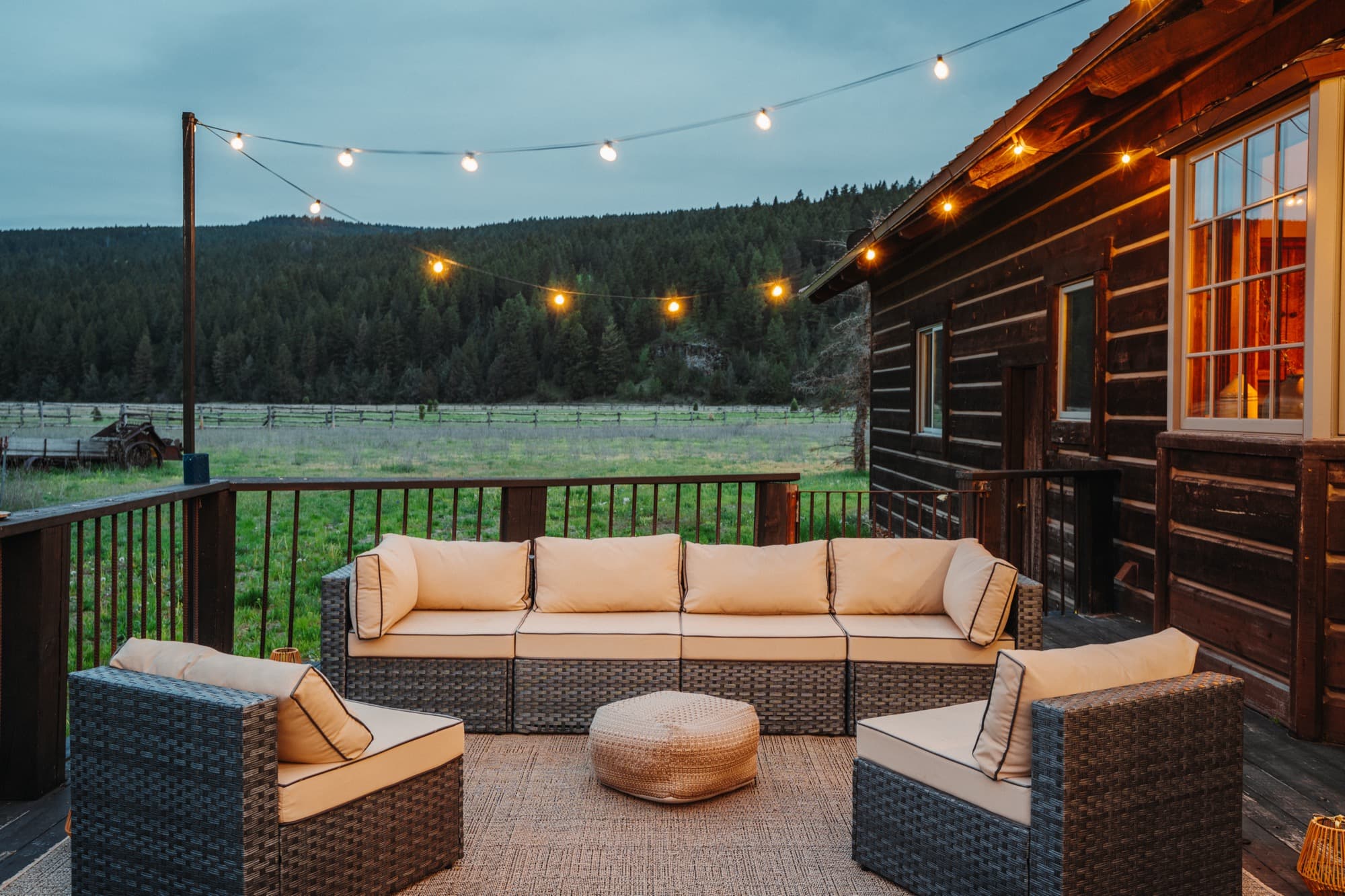 Deck lounge seating under string lights at dusk with mountain views